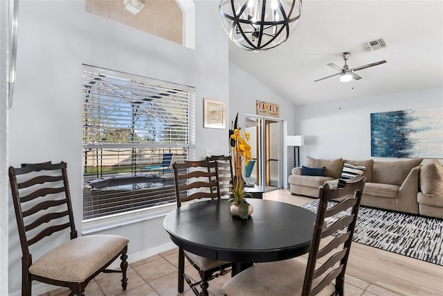 dining area featuring ceiling fan with notable chandelier, light wood-type flooring, and vaulted ceiling