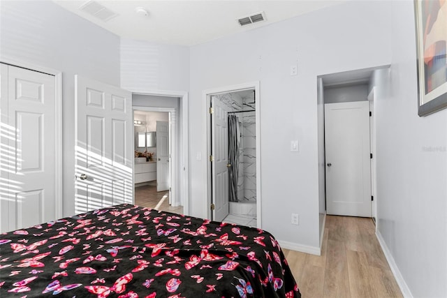 bedroom with ensuite bathroom and light hardwood / wood-style flooring