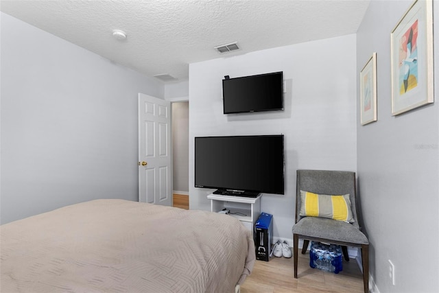 bedroom featuring light hardwood / wood-style floors and a textured ceiling