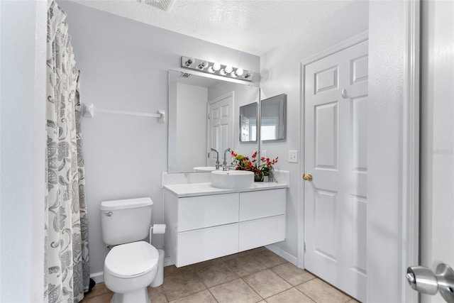 bathroom with tile patterned floors, vanity, toilet, and a textured ceiling