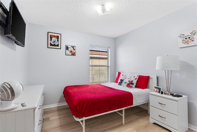 bedroom featuring a textured ceiling and light hardwood / wood-style flooring