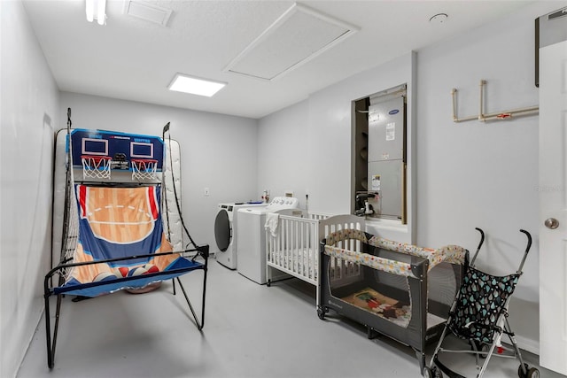 bedroom featuring concrete floors, a nursery area, and washing machine and clothes dryer