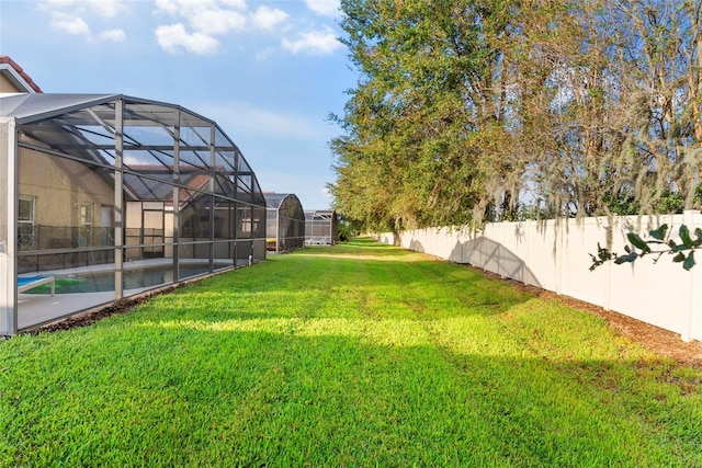 view of yard with a fenced in pool and glass enclosure