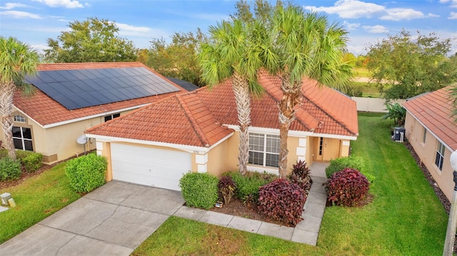 mediterranean / spanish-style house featuring solar panels, a front yard, and a garage