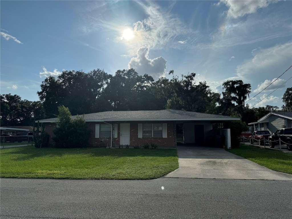 ranch-style house featuring driveway, a carport, and a front yard