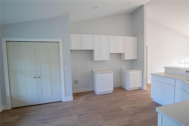 kitchen with white cabinets, light hardwood / wood-style flooring, and vaulted ceiling