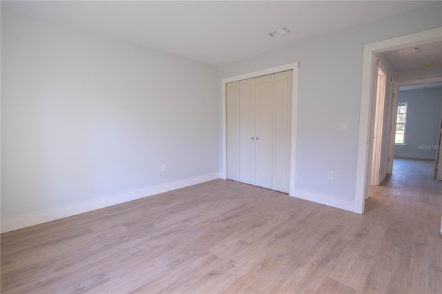 unfurnished bedroom featuring light hardwood / wood-style flooring and a closet