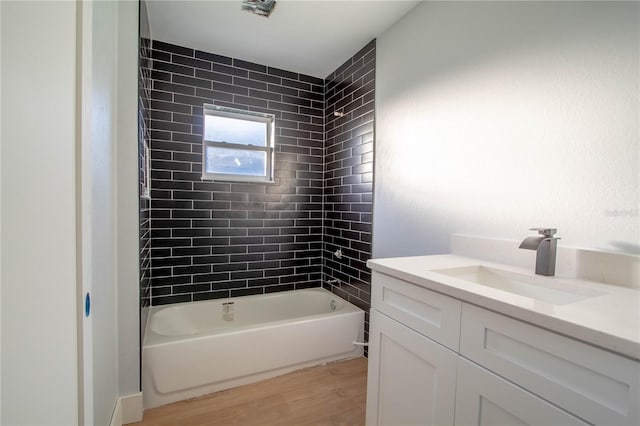 bathroom with hardwood / wood-style flooring, vanity, and tiled shower / bath