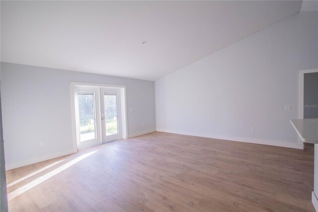 unfurnished living room featuring lofted ceiling, wood-type flooring, and french doors