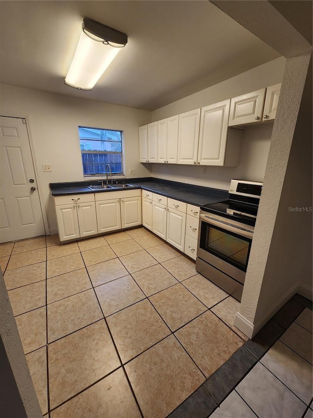 kitchen with sink, white cabinetry, stainless steel range with electric cooktop, and light tile patterned floors