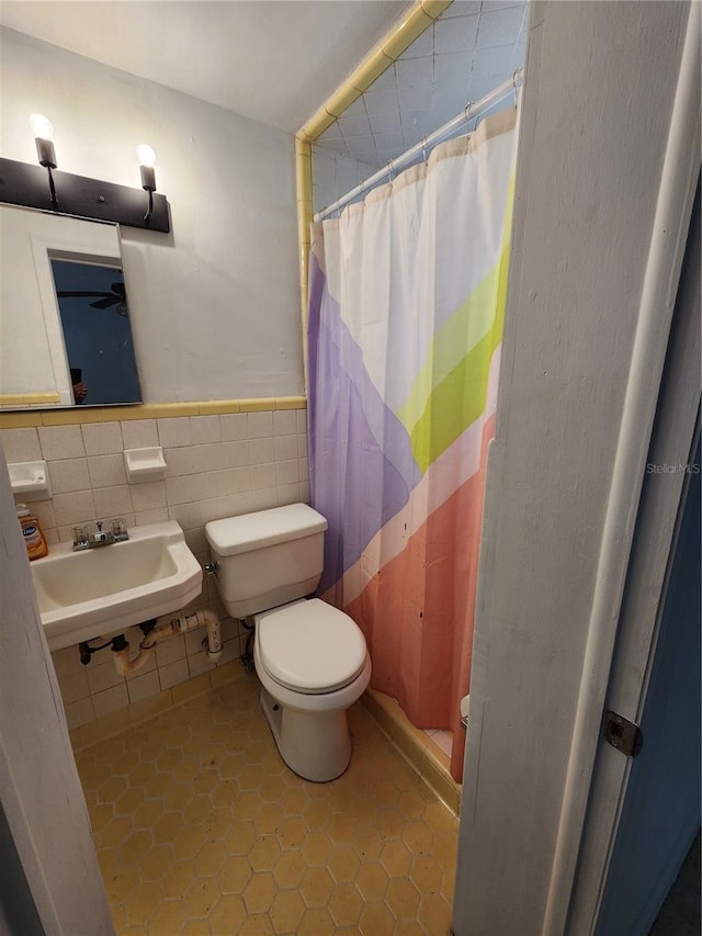 bathroom featuring curtained shower, sink, tile patterned flooring, toilet, and tile walls