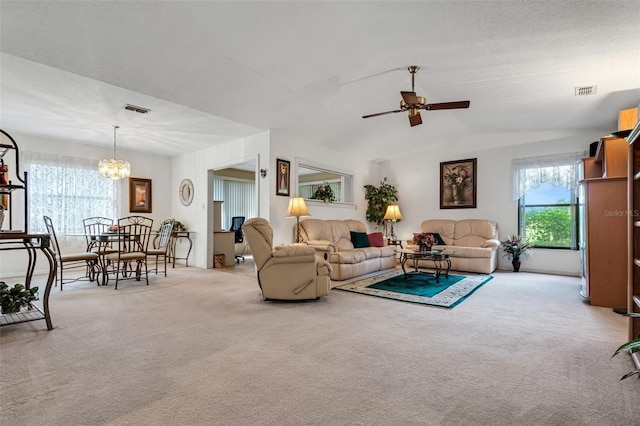 carpeted living room featuring ceiling fan with notable chandelier and vaulted ceiling