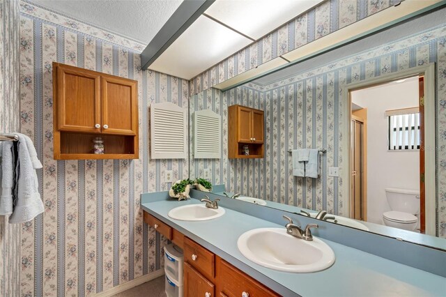 bathroom with a textured ceiling, vanity, and toilet