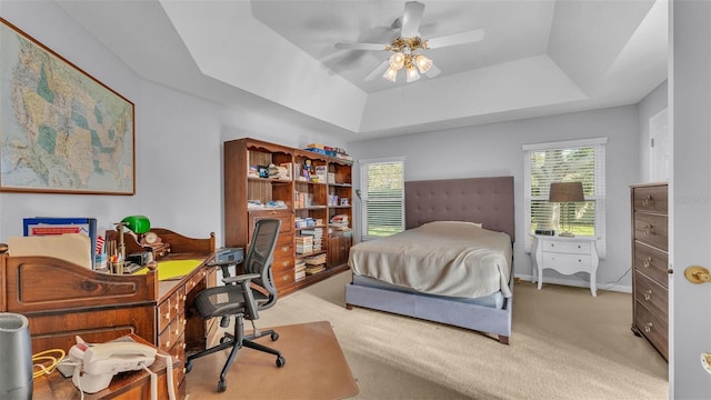 carpeted bedroom featuring a tray ceiling and ceiling fan