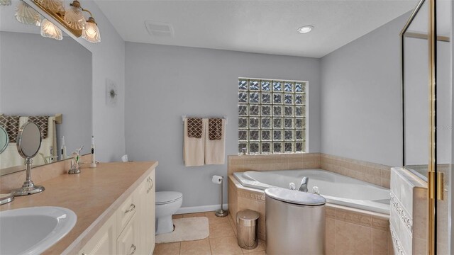 bathroom featuring tile patterned floors, tiled tub, vanity, and toilet