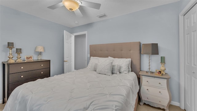 bedroom with ceiling fan, light carpet, and a closet