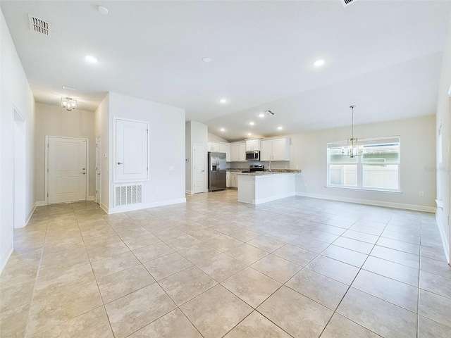 unfurnished living room featuring a notable chandelier, light tile patterned flooring, lofted ceiling, and sink