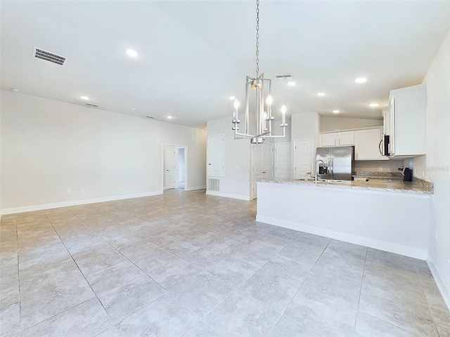 kitchen featuring light stone countertops, appliances with stainless steel finishes, vaulted ceiling, white cabinets, and hanging light fixtures