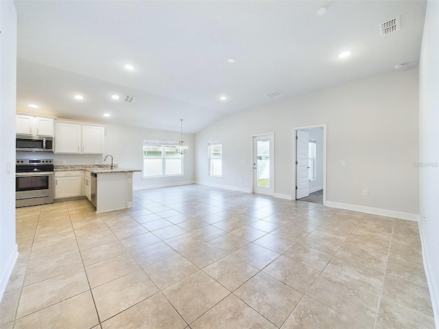 kitchen with lofted ceiling, white cabinets, light tile patterned floors, appliances with stainless steel finishes, and light stone counters