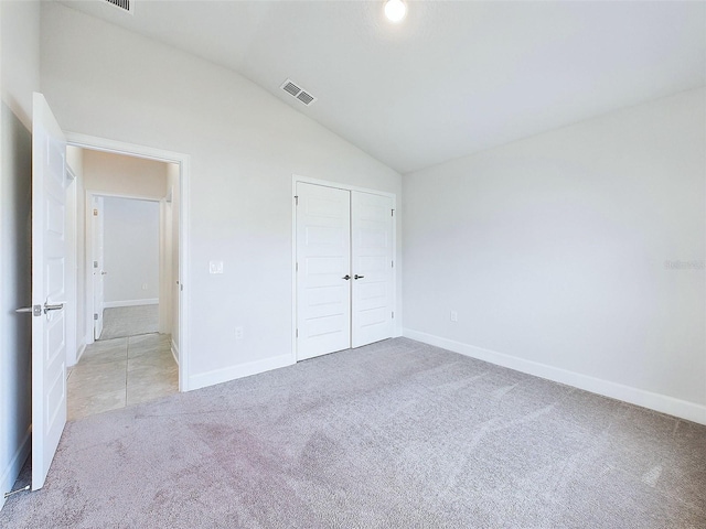 unfurnished bedroom with light colored carpet, lofted ceiling, and a closet