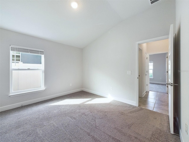 empty room featuring light colored carpet and vaulted ceiling