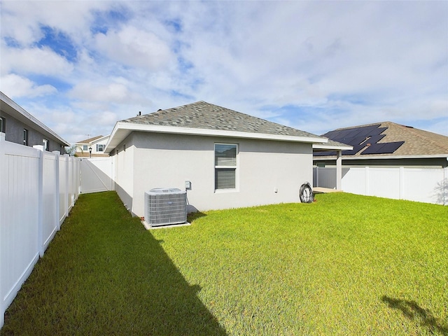 back of property with a lawn and central AC