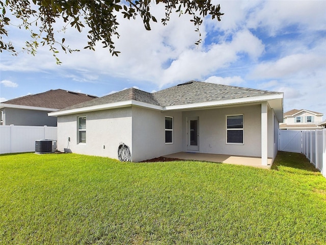 rear view of property featuring a lawn, cooling unit, and a patio