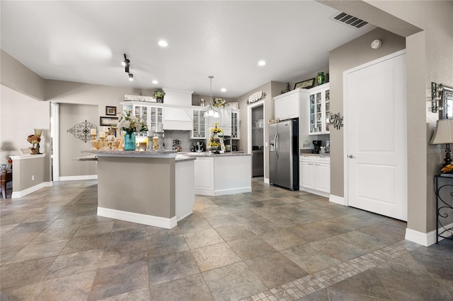 kitchen featuring an inviting chandelier, hanging light fixtures, stainless steel fridge, a kitchen island, and white cabinetry