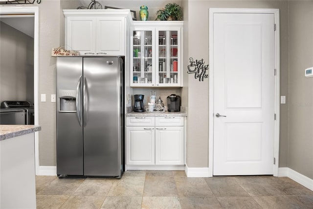 kitchen with washer and clothes dryer, white cabinetry, and stainless steel fridge with ice dispenser