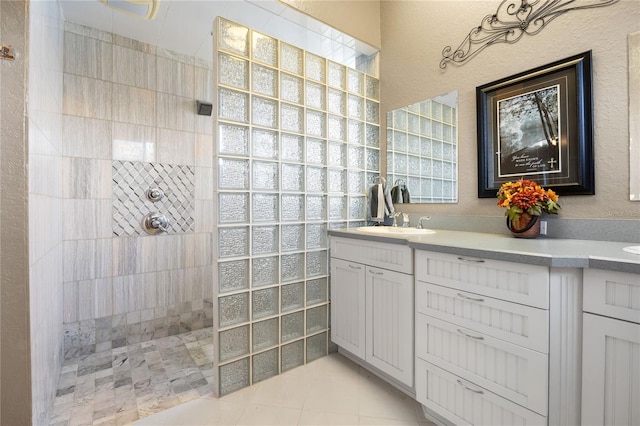 bathroom with tile patterned floors, vanity, and tiled shower