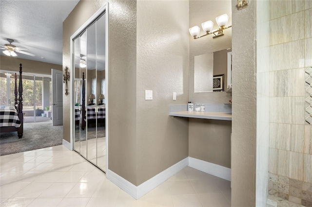 bathroom with tile patterned flooring, a textured ceiling, and ceiling fan