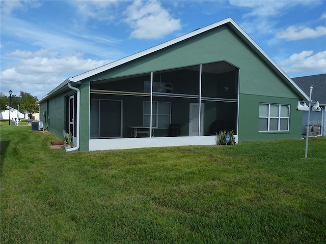 rear view of house with a sunroom, central AC unit, and a lawn