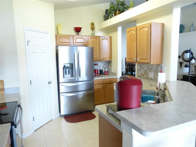 kitchen with backsplash, kitchen peninsula, stainless steel fridge, and range