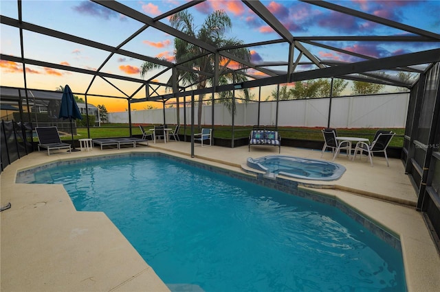 pool at dusk featuring an in ground hot tub, a patio, and glass enclosure