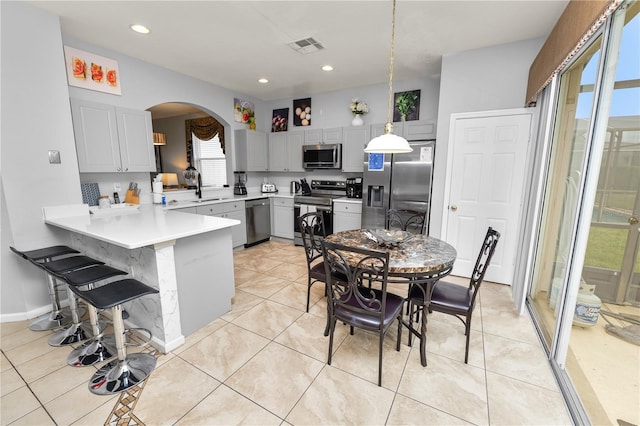 kitchen with pendant lighting, gray cabinetry, kitchen peninsula, and stainless steel appliances