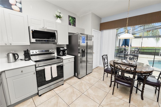 kitchen with white cabinets, light tile patterned flooring, stainless steel appliances, and hanging light fixtures