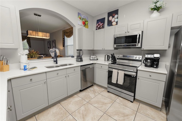 kitchen with white cabinets, sink, light tile patterned floors, decorative light fixtures, and stainless steel appliances