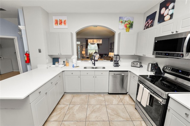 kitchen featuring kitchen peninsula, appliances with stainless steel finishes, sink, white cabinets, and washer / clothes dryer