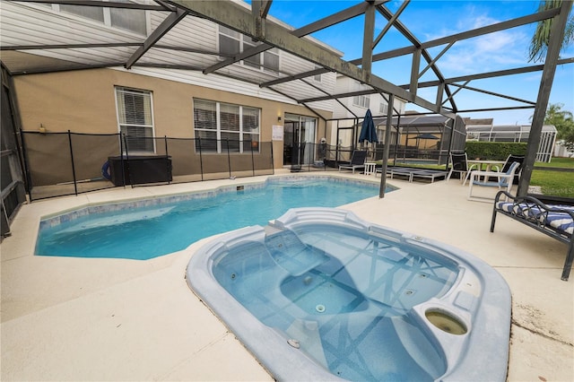 view of pool with glass enclosure, a patio area, and an in ground hot tub