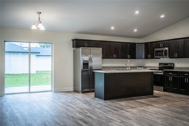 kitchen with stainless steel appliances, hanging light fixtures, light wood-style flooring, a sink, and an island with sink