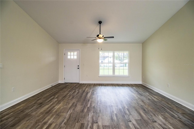 interior space with a ceiling fan, vaulted ceiling, dark wood finished floors, and baseboards