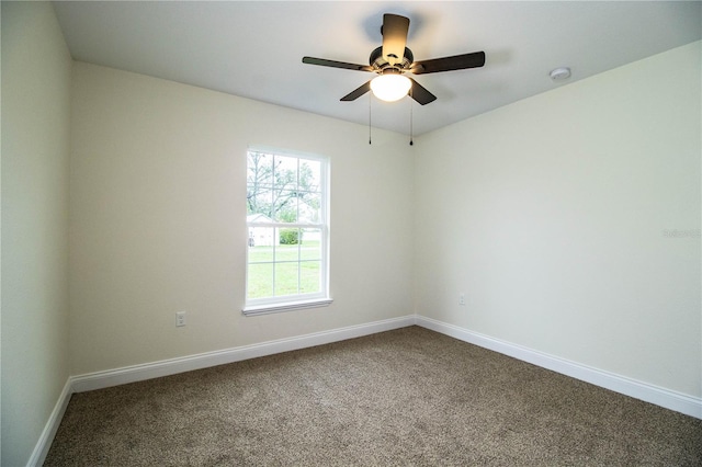 unfurnished room with a ceiling fan, dark colored carpet, and baseboards