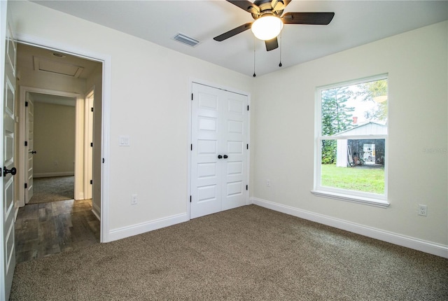 unfurnished bedroom featuring baseboards, visible vents, dark colored carpet, and a closet