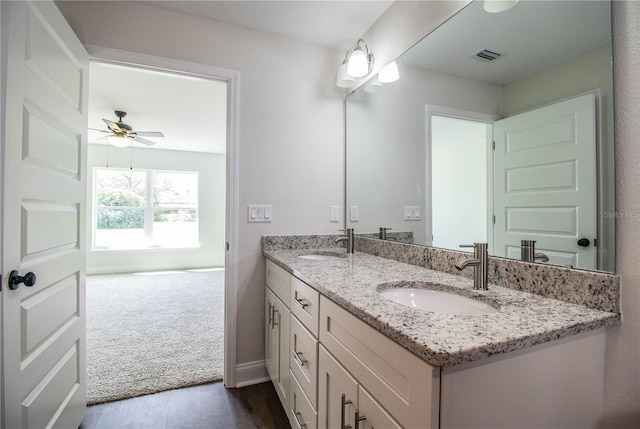 full bath with ceiling fan, double vanity, wood finished floors, and a sink