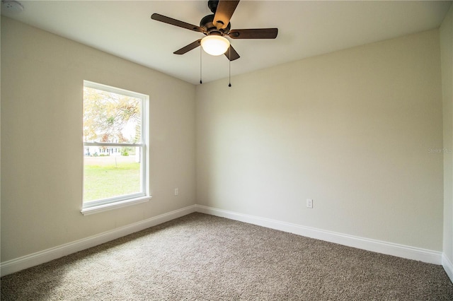 carpeted spare room featuring ceiling fan and baseboards