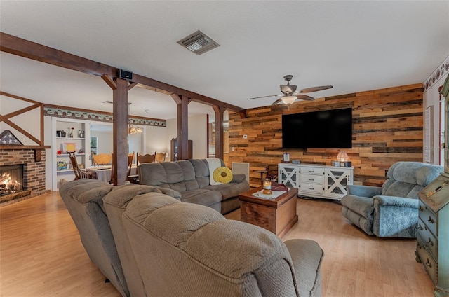 living room featuring a brick fireplace, decorative columns, light hardwood / wood-style flooring, and wood walls