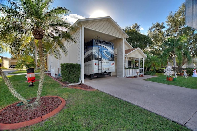 view of side of home with covered porch, a carport, and a lawn