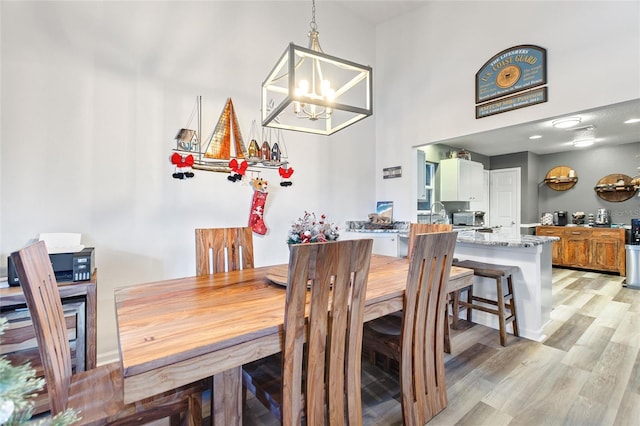 dining space featuring light hardwood / wood-style floors, a towering ceiling, and a chandelier