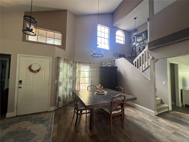 dining area with hardwood / wood-style floors, a textured ceiling, high vaulted ceiling, and a notable chandelier