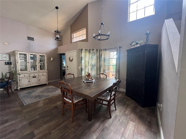 dining area with high vaulted ceiling, dark wood-type flooring, and a notable chandelier